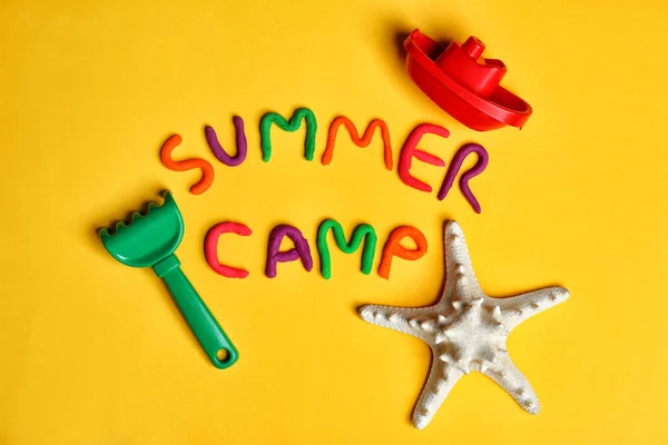 Composição de leigos planos com palavras SUMMER CAMP feitas de modelagem de brinquedos de argila e praia no fundo de cor — Fotografia de Stock