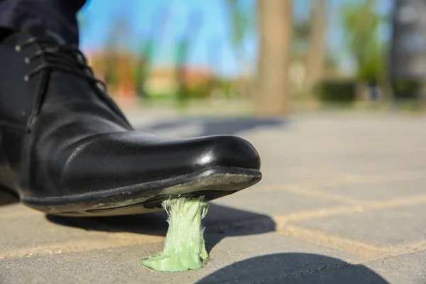 Man stepping in chewing gum on sidewalk. Concept of stickiness