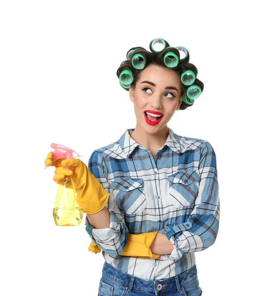 Engraçado jovem dona de casa com rolos de cabelo segurando detergente no fundo branco — Fotografia de Stock