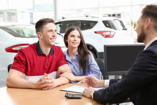 Ungt par som kjøper ny bil hos bilforhandlere – stockfoto