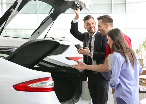 Pareja joven comprando coche nuevo en el salón — Foto de Stock