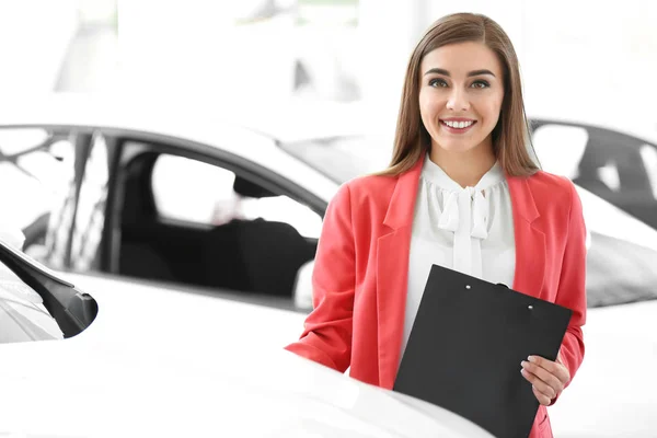 Mujer joven con portapapeles en salón de coches — Foto de Stock