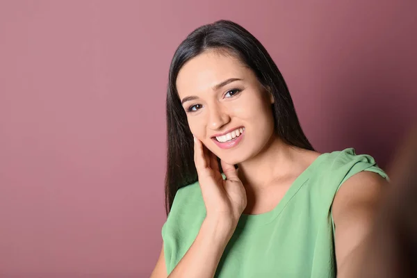 Jong mooi vrouw het nemen van selfie tegen kleur achtergrond — Stockfoto