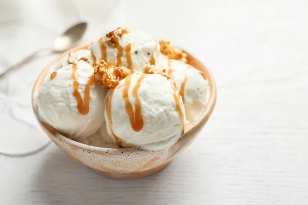 Gustoso gelato con salsa al caramello e popcorn in ciotola sul tavolo — Foto Stock