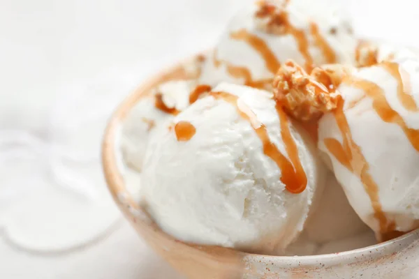 Вкусное мороженое с карамельным соусом и попкорном в миске на столе, крупным планом — стоковое фото
