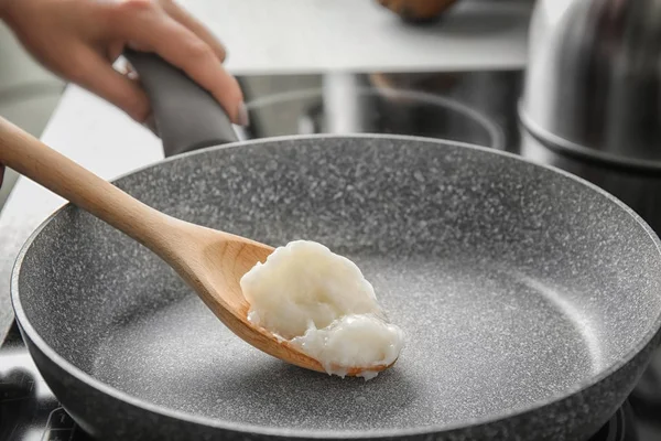 Женщина готовит с кокосовым маслом в сковороде — стоковое фото