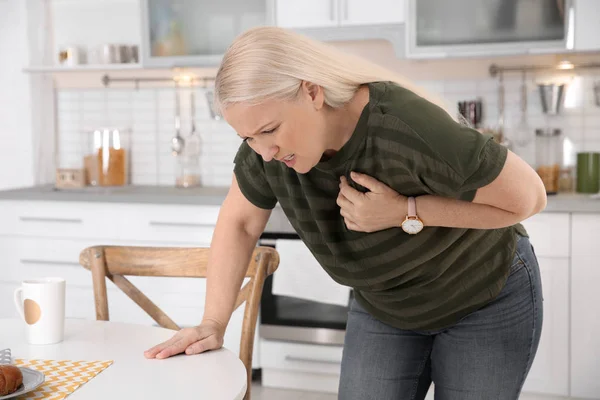 Mulher madura tendo ataque cardíaco na cozinha — Fotografia de Stock
