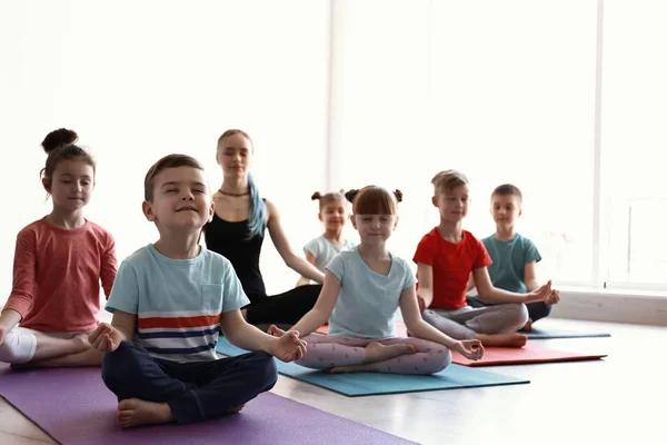 Los niños pequeños y su profesor practican yoga en el gimnasio — Foto de Stock