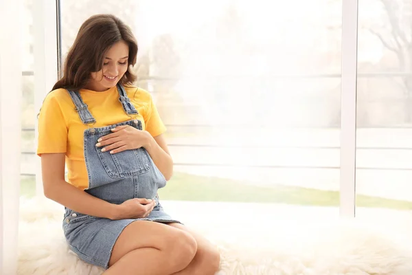 Belle femme enceinte assise près de la fenêtre à la maison — Photo