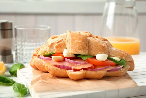 Leckeres Croissant-Sandwich mit Lachs auf dem Tisch — Stockfoto