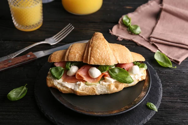 Leckeres Croissant-Sandwich mit Lachs auf dem Tisch — Stockfoto