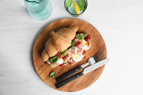 Leckeres Croissant-Sandwich mit Speck auf Holzhintergrund, Draufsicht — Stockfoto