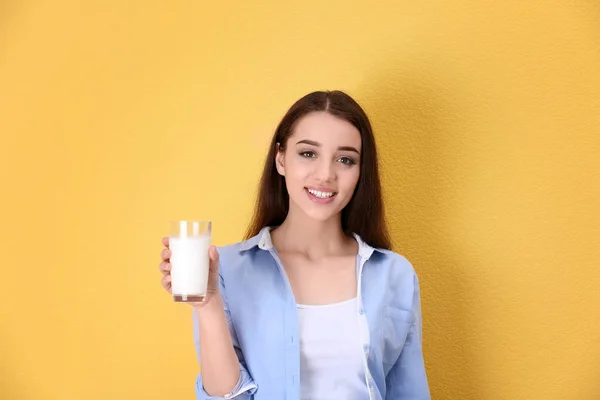 美しい若い女性は色の背景にミルクを飲む — ストック写真