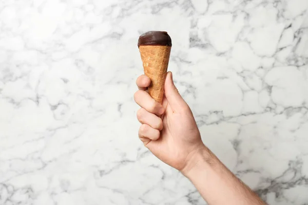 Uomo in possesso di gelato gustoso su sfondo di marmo. Focus a portata di mano — Foto Stock