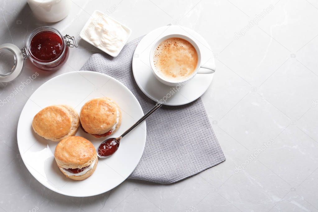Tasty scones with clotted cream and jam on grey background, top view