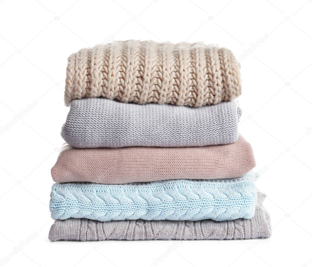 Stack of warm knitted clothes on white background