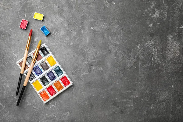 Műanyag paletta a színes festékek és ecsetek asztalon, felülnézet — Stock Fotó