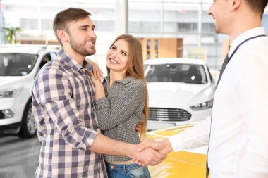 Genç adam araba salonda satıcı ile el sıkışan