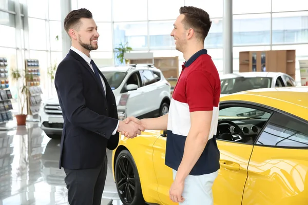 Young man buying car in salon