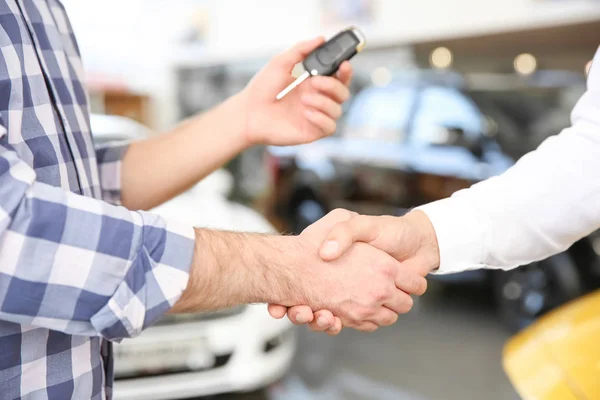 Joven estrechando la mano con el vendedor en el salón de coches — Foto de Stock
