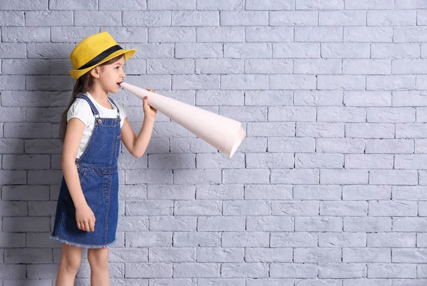 Aranyos kislány papír megafon téglafal háttér — Stock Fotó