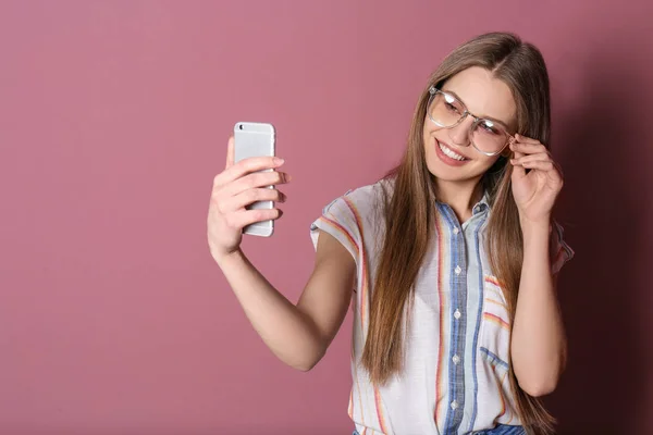 Junge schöne Frau macht Selfie vor farbigem Hintergrund — Stockfoto