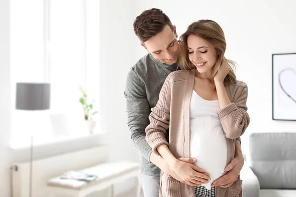 Mladá těhotná žena se svým manželem doma — Stock fotografie