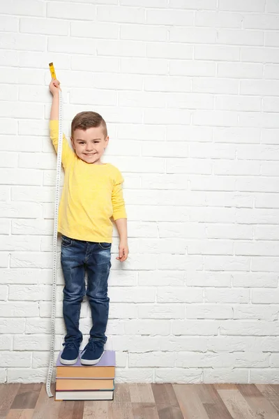 Niño midiendo su altura cerca de la pared de ladrillo — Foto de Stock