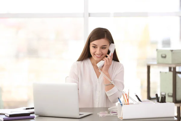 Mujer joven hablando por teléfono en el lugar de trabajo — Foto de Stock
