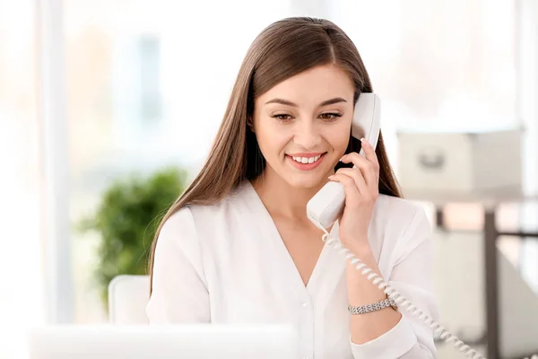 Young woman talking on phone at workplace — Stock Photo, Image