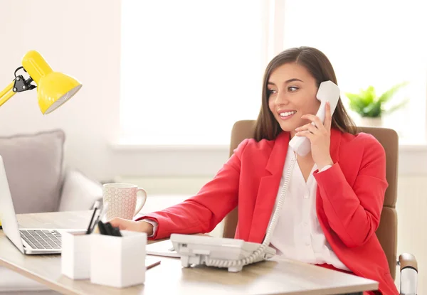 Mujer joven hablando por teléfono en el lugar de trabajo — Foto de Stock