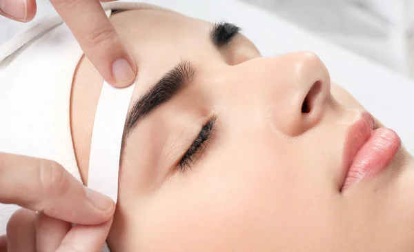 Young woman having professional eyebrow correction procedure in beauty salon, closeup — Stock Photo, Image