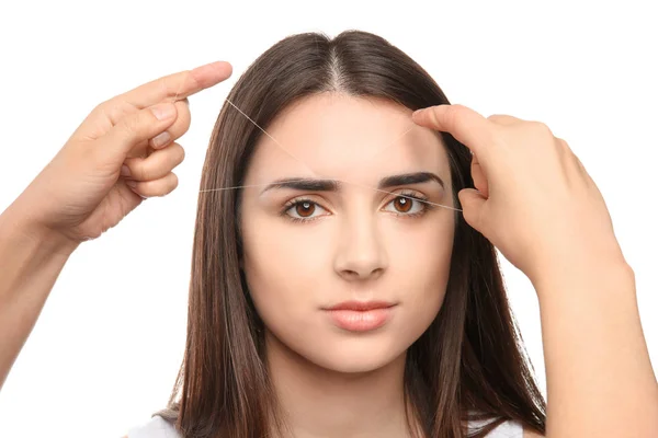Молода жінка має процедуру корекції брів на білому тлі — стокове фото