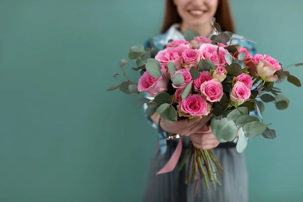 Kvinnliga florist holding bukett med vackra blommor på färgbakgrund — Stockfoto