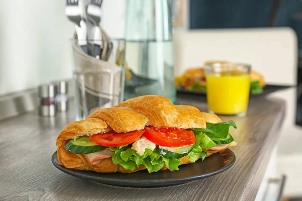 Leckeres Croissant-Sandwich mit Wurst auf dem Tisch — Stockfoto