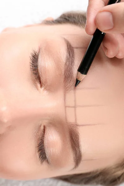 Young woman having eyebrow correction procedure in beauty salon, closeup