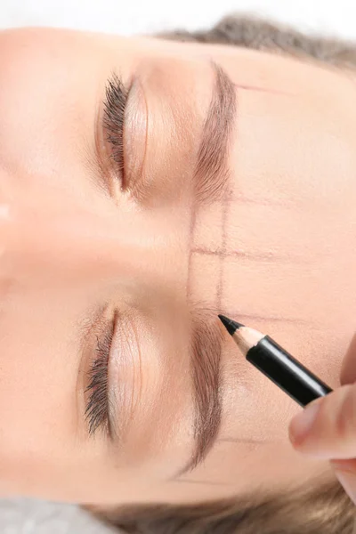 Young woman having eyebrow correction procedure in beauty salon, closeup