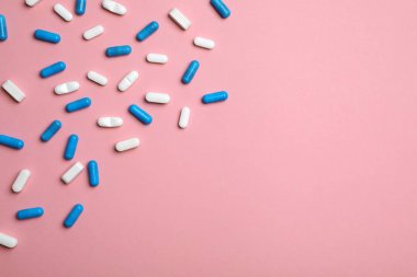 Farklı hap ve kapsül düz renkli arka plan üzerinde yatıyordu