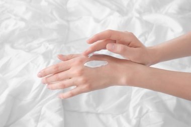 Genç kadın kapalı eller üzerine krem uygulamak