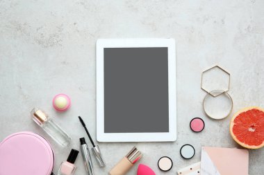 Gri zemin üzerine tablet ve makyaj ürünleri ile düz yatıyordu kompozisyon
