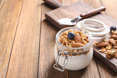 Yoğurt, fındık ve granola ahşap masa üzerinde kavanoz