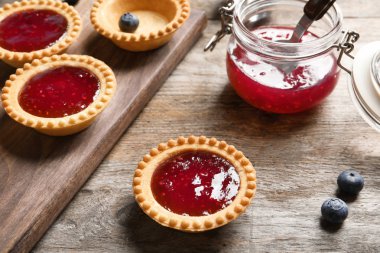 Ahşap arka plan üzerinde reçelli lezzetli tartlets