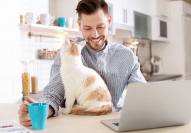 Genç adam şirin kedi ve dizüstü evde