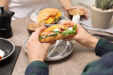 Lezzetli kruvasan sandviç tablo plaka üzerinde tutan adam