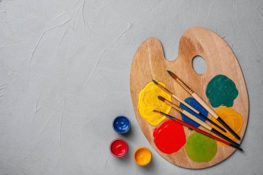 Renkli boya ve fırça gri arka planda, üstten görünüm ile ahşap palet