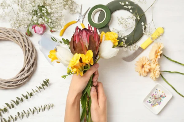 Female florist making beautiful bouquet at table, top view — Stock Photo, Image
