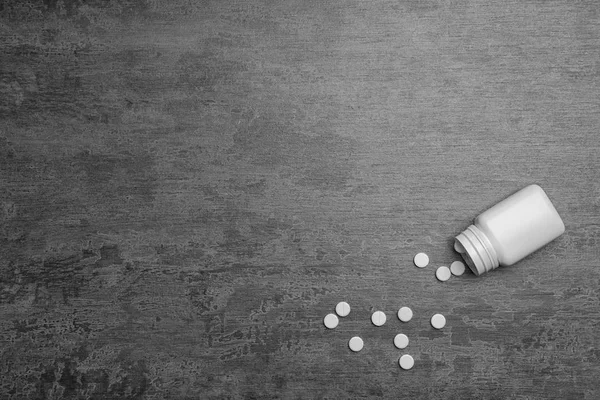 Behållare med vita piller på grå bakgrund — Stockfoto