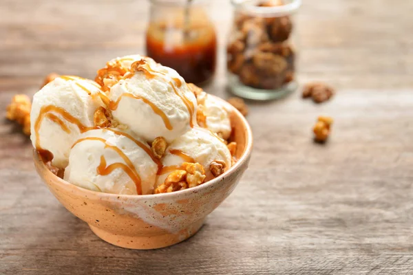 Gustoso gelato con salsa al caramello e popcorn in ciotola sul tavolo di legno — Foto Stock