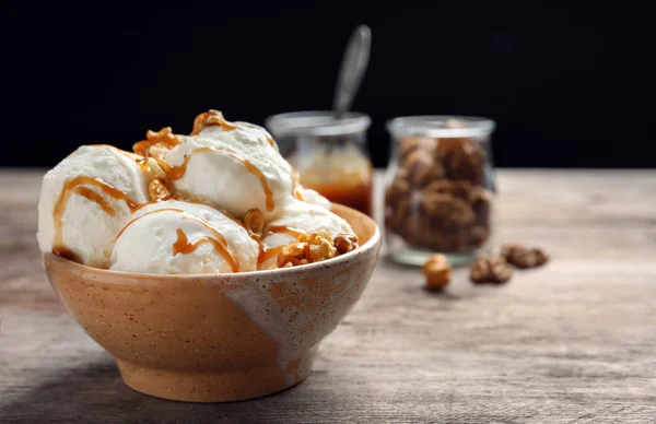 Вкусное мороженое с карамельным соусом и попкорном в миске на деревянном столе — стоковое фото