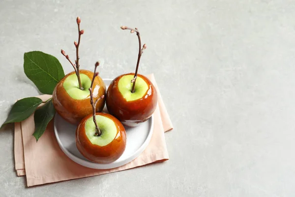 Placa con deliciosas manzanas de caramelo verde en la mesa — Foto de Stock